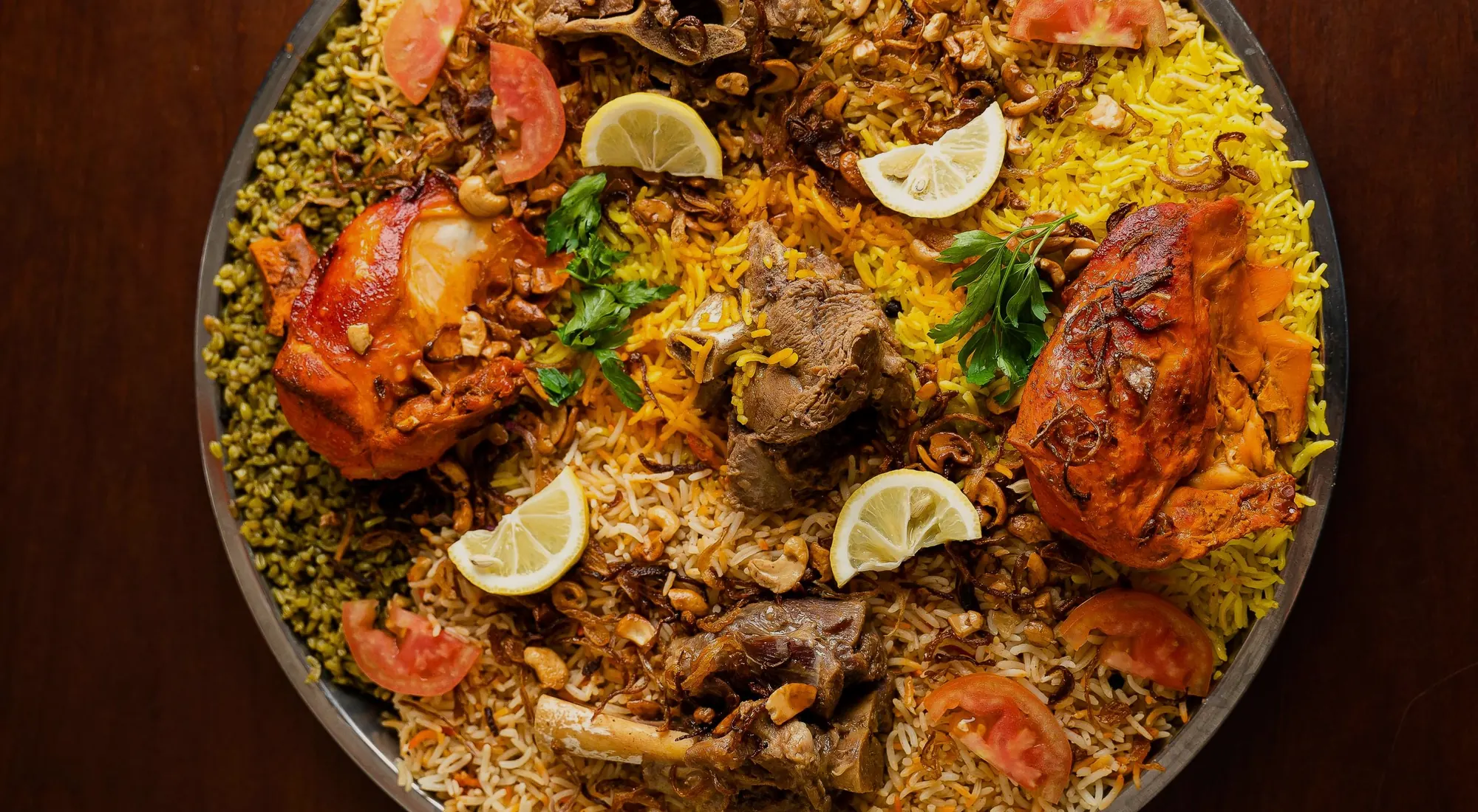 A shared platter of mandi rice with roast chicken and lamb, lemon and tomato