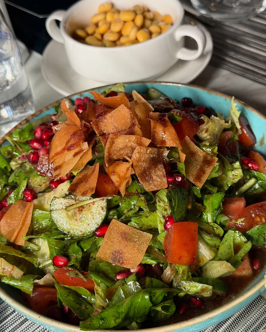 Fattoush salad with crisp bread and pomegranate seeds, a bowl of chickpeas behind