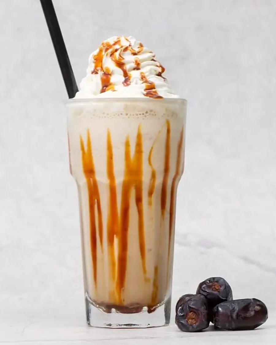 A tall dates ice blended with whipped cream and caramel, dates beside the glass
